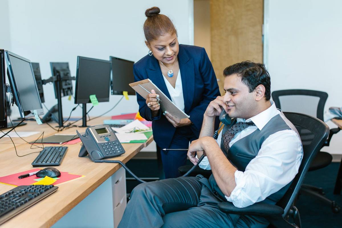 Two colleagues at an office desk going over something on a tablet