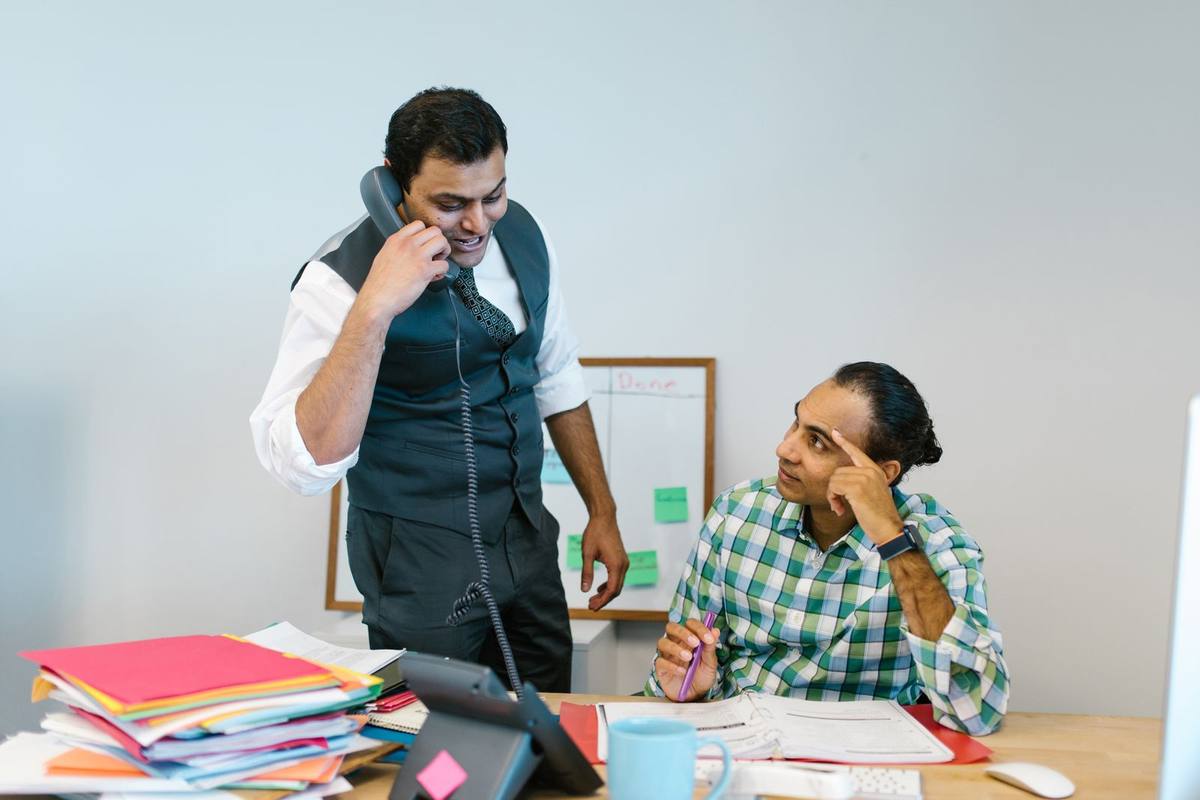Two colleagues at work in an Indian office, one on a phone call