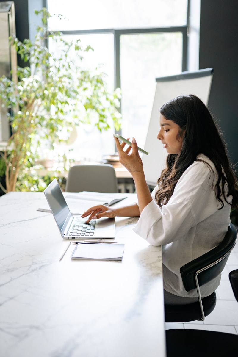 A woman at her office desk with her phone and laptop