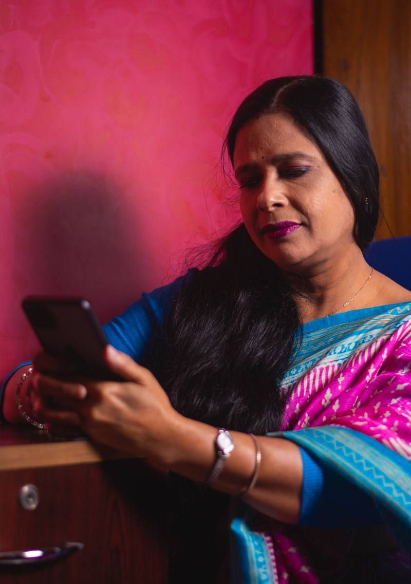 A woman in a saree reading something on her smartphone