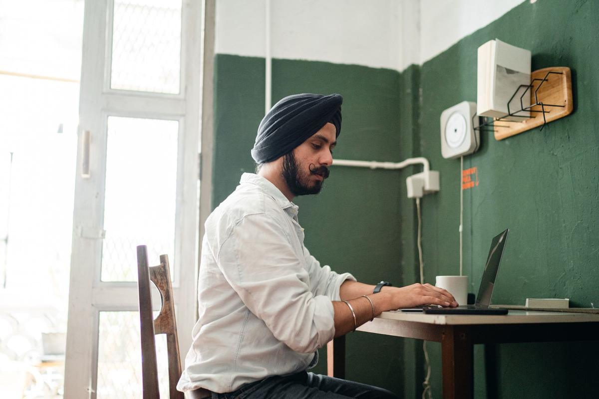 A man in a small Indian office working on his laptop